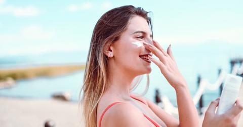 Woman putting sunscreen on face on a beach