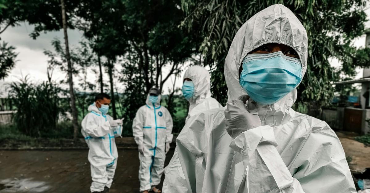 People wear PPE while huddling outside together