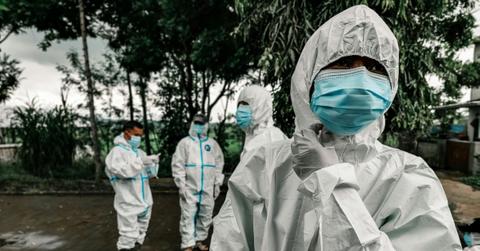 People wear PPE while huddling outside together