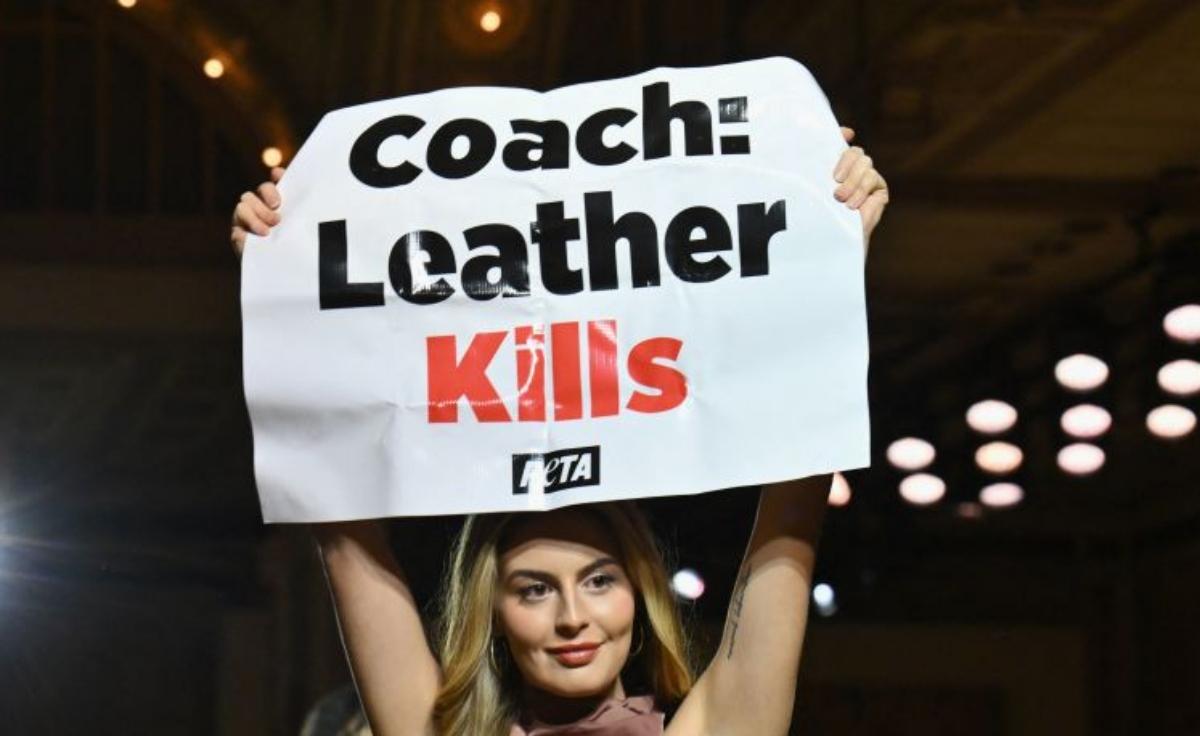 woman holds a PETA sign reading "Coach: Leather Kills"