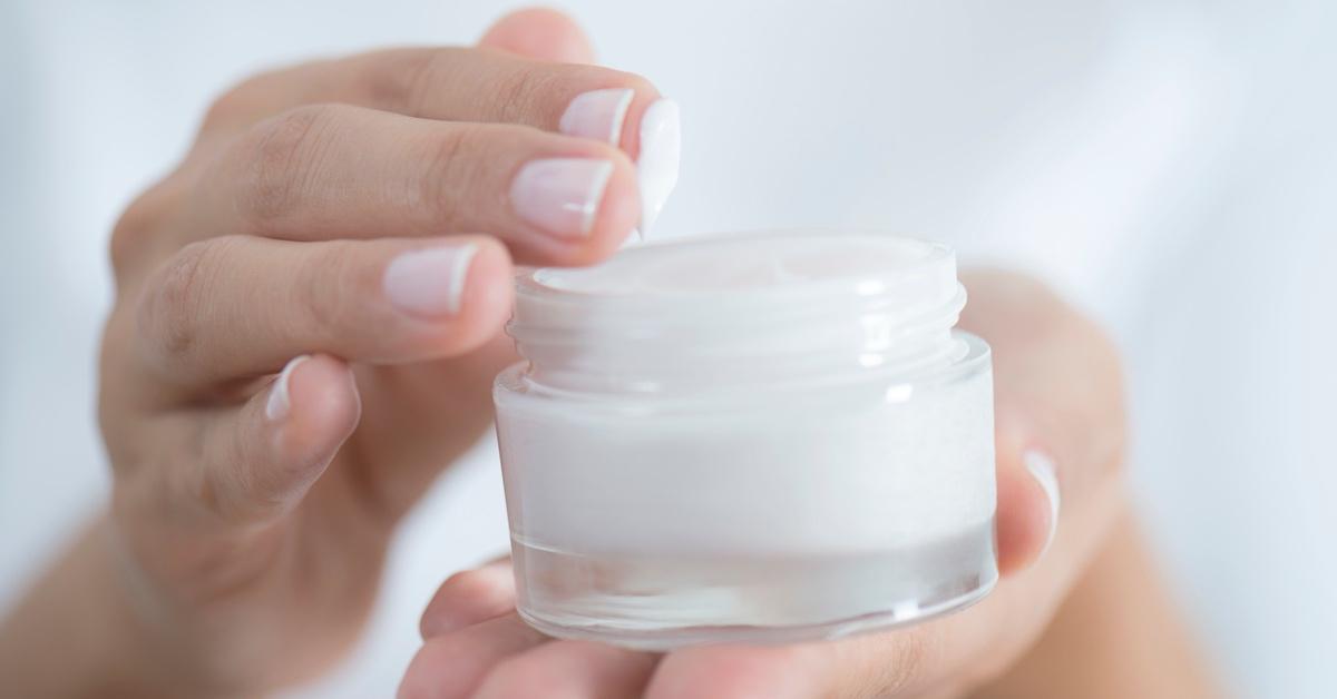 Woman applying cream from a jar