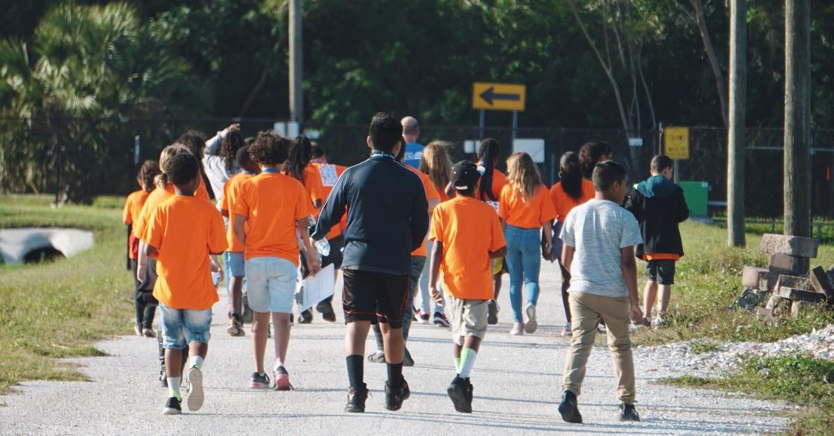 Kids in orange shirts run a race at school
