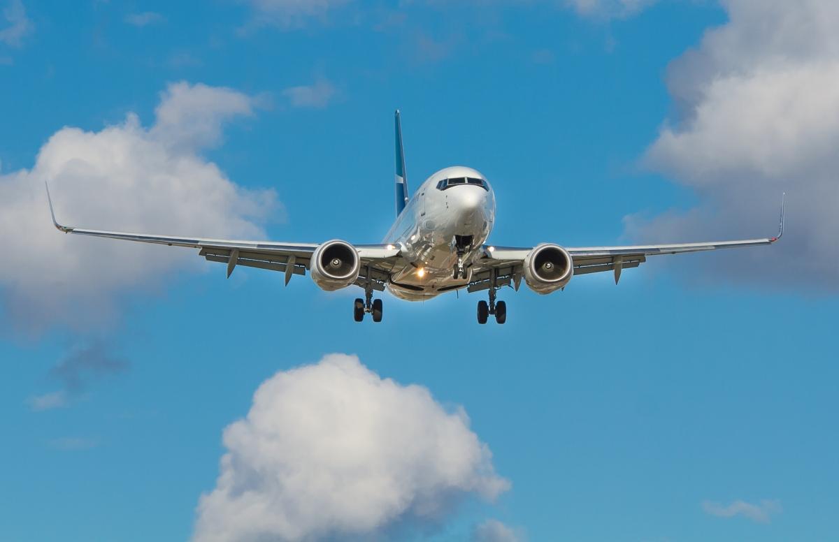 Large aircraft flying in a blue sky with few clouds.