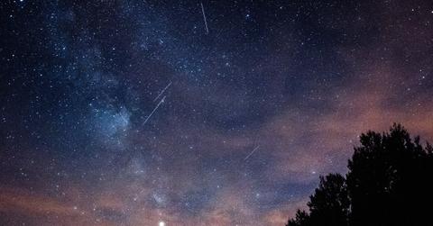 Meteors streak across a pink and blue night sky