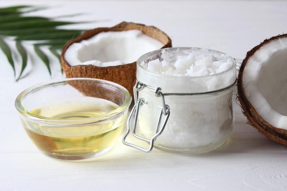 Coconuts and coconut oil on a white countertop.