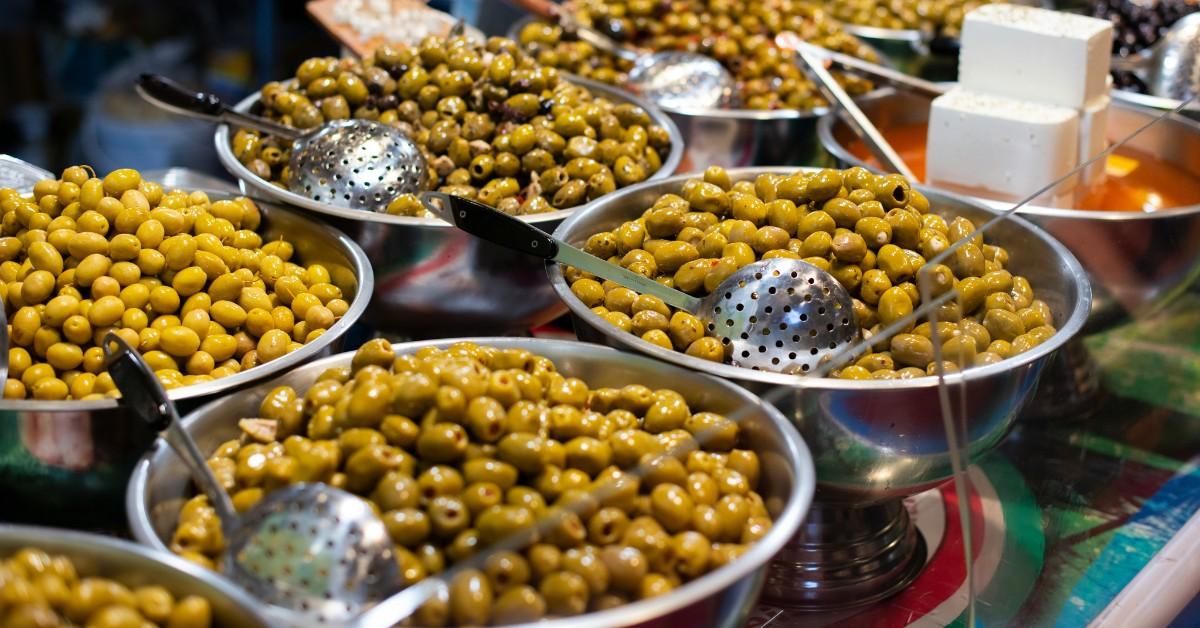 A salad bar is covered in bowls of different varieties of olives