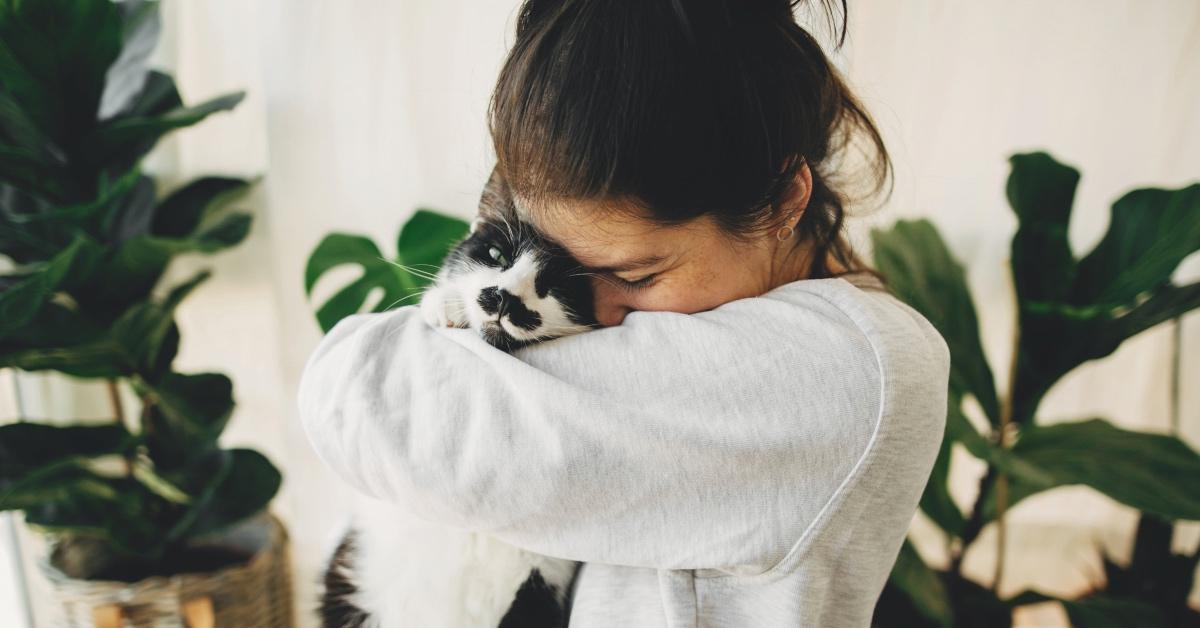 Woman cuddling black and white cat. 