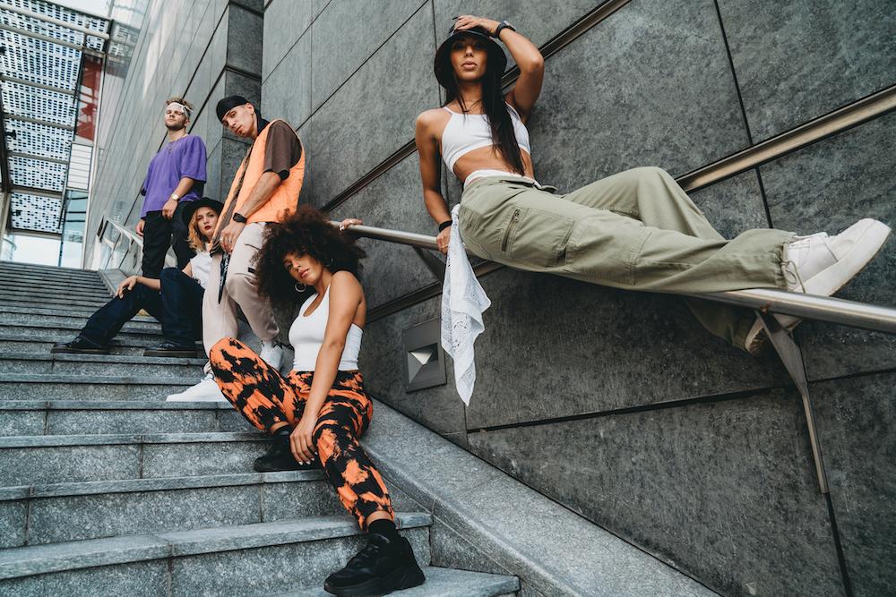 A trendy group of young people pose on a stairwell. 