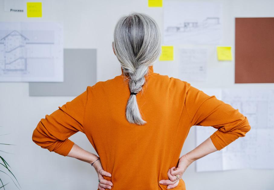 A woman with grey hair looking at a board.