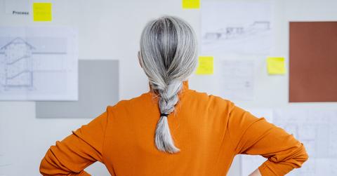 A woman with grey hair looking at a board.