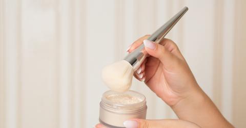 Hands holding makeup and brush.