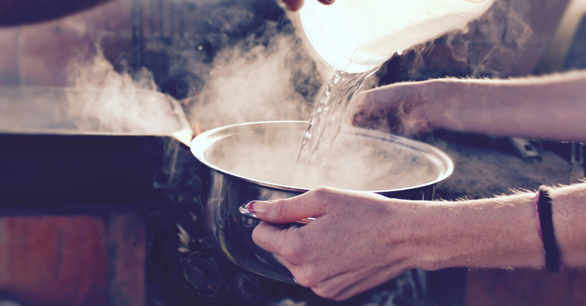 Man pours cold water into a pot of boiling water