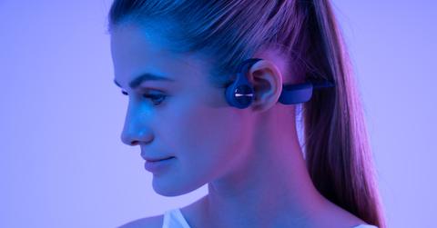 Woman in neon light wearing sport bone conduction headphones during fitness workout