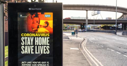 A sign that reads "coronoavirus: stay home, save lives" on the side of a road