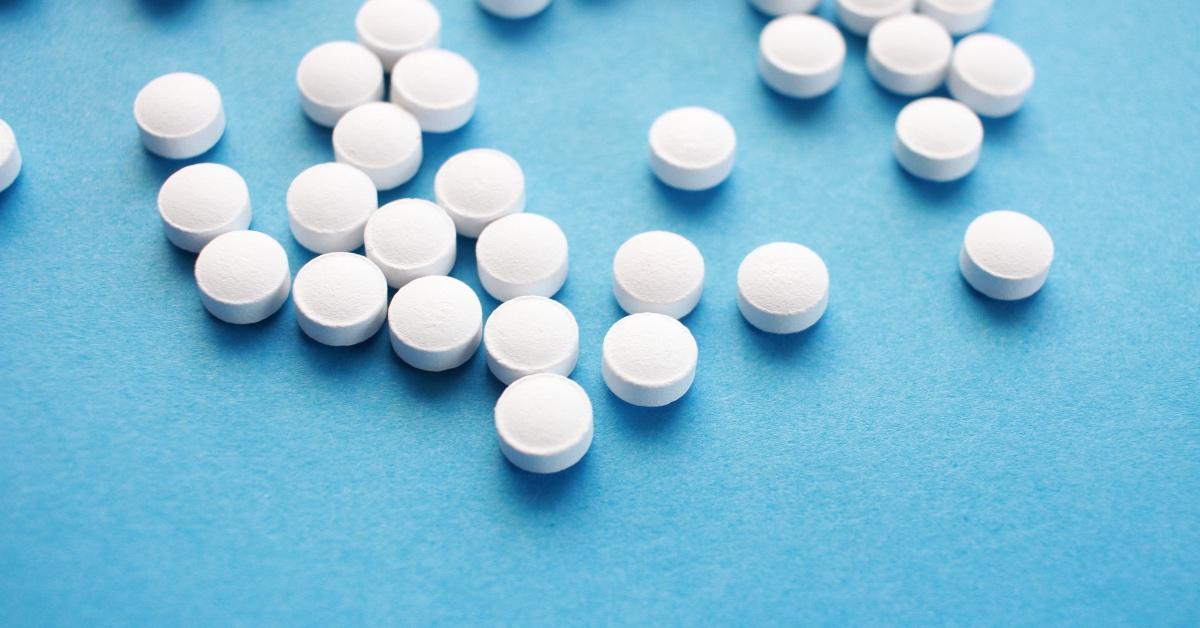 Photograph of pills spilled out on a blue counter. 