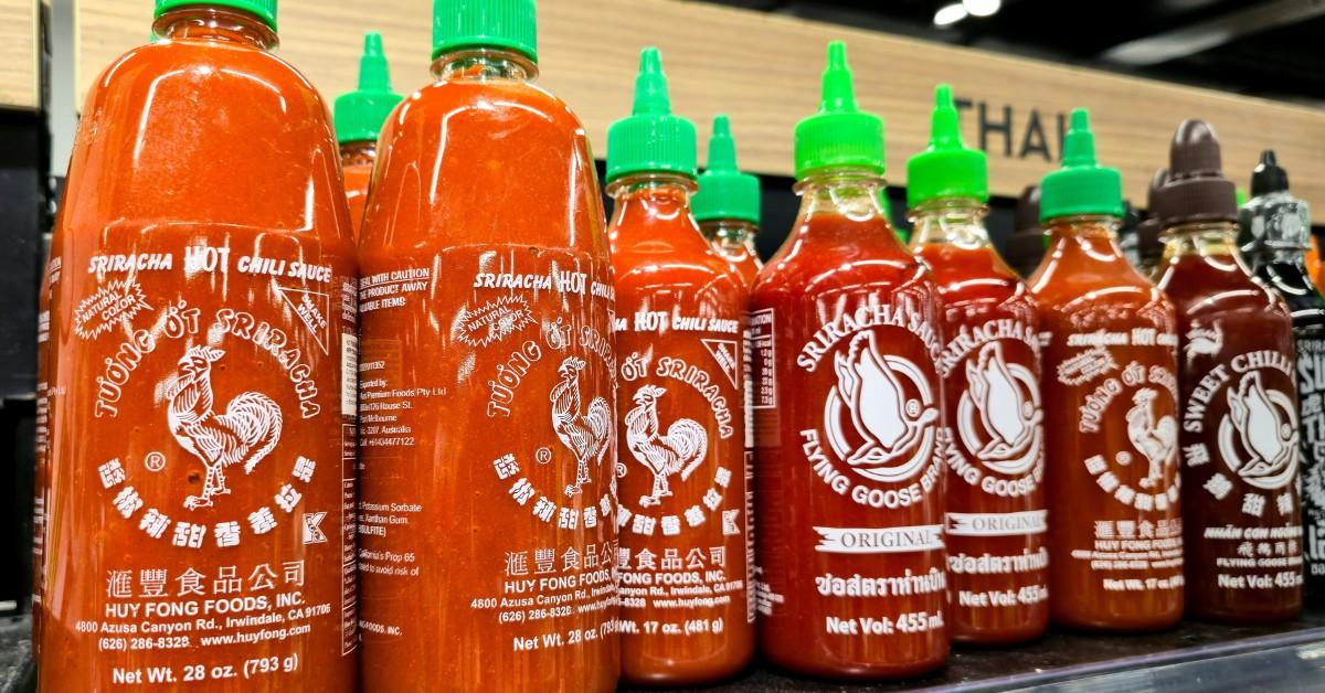 Bottles of Sriracha are lined up on the shelf at the store