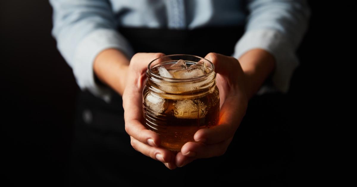 Barista holding a cup of iced kombucha. 