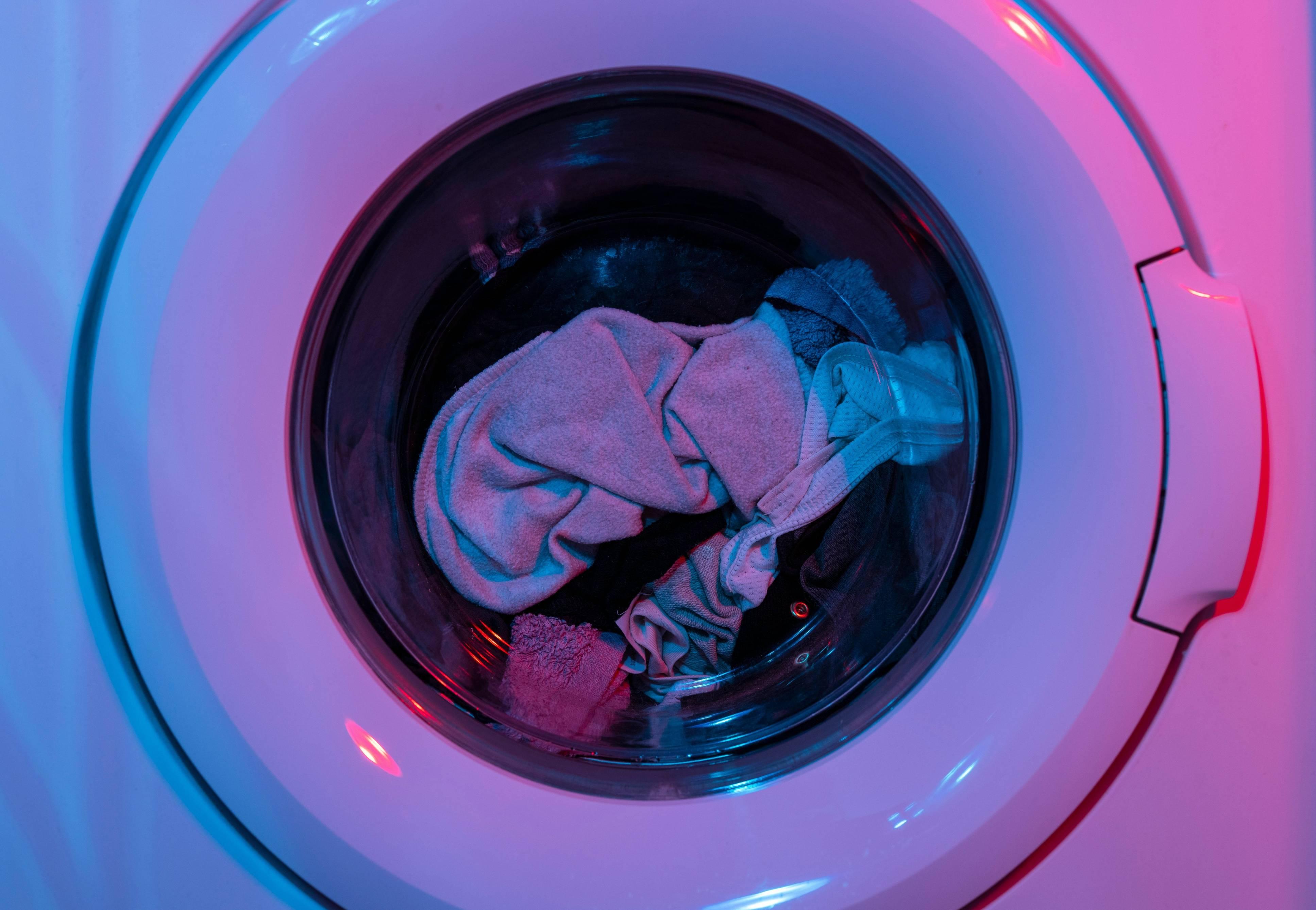 A series of clothes are depicted in a dryer, which is one method to shrink a shirt.