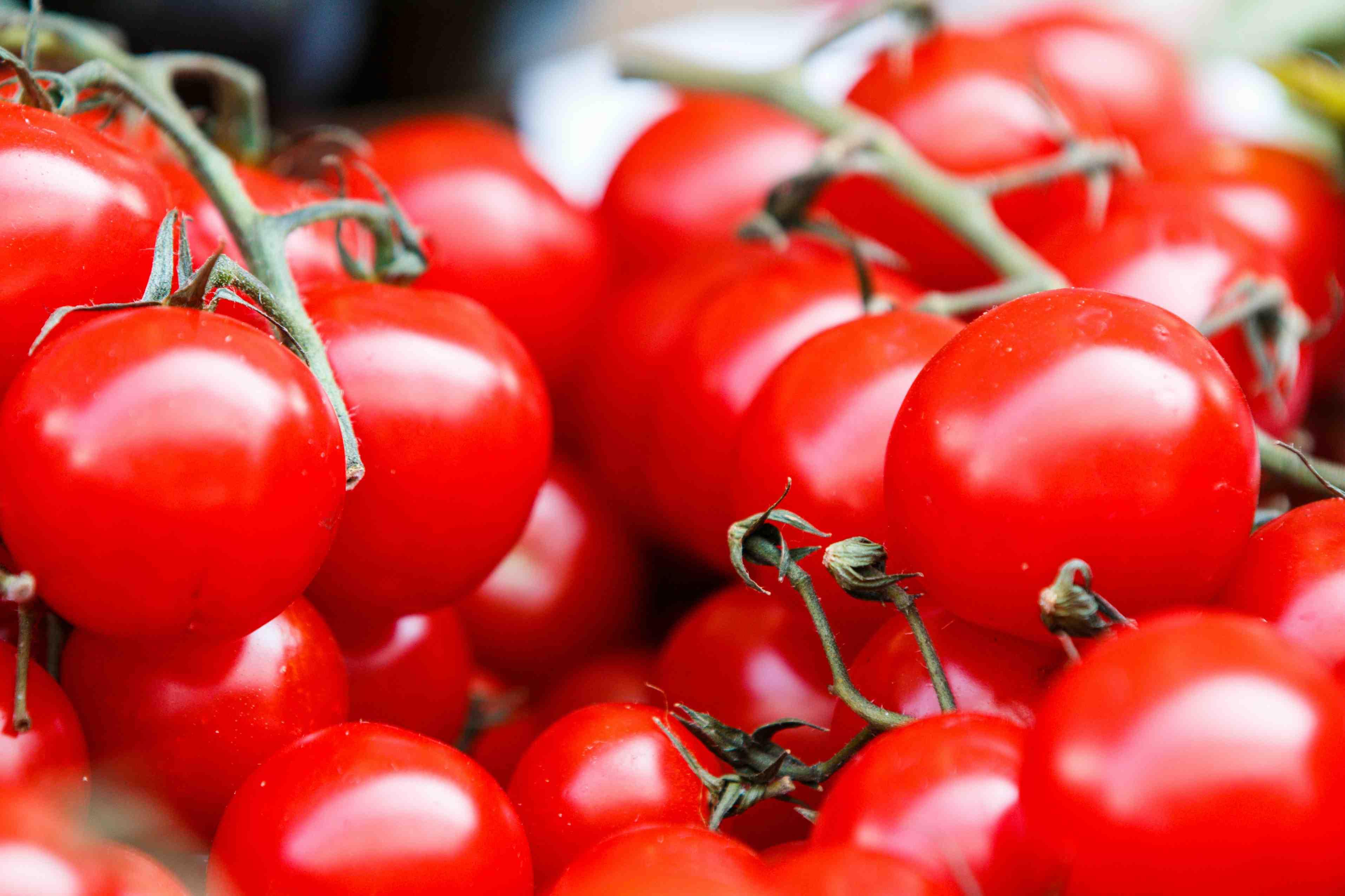 A bunch of tomatoes are piled atop one another.