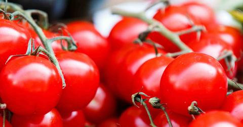 A bunch of tomatoes are piled atop one another.