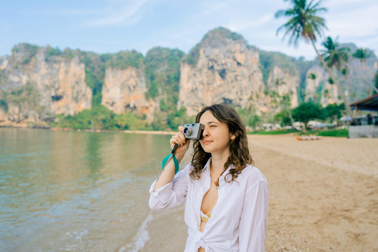 Person on a beach using a digital camera to take a photo.