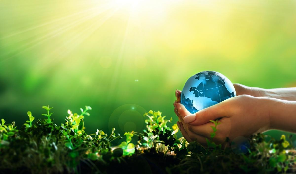 person holding Earth in her hands with sun shining