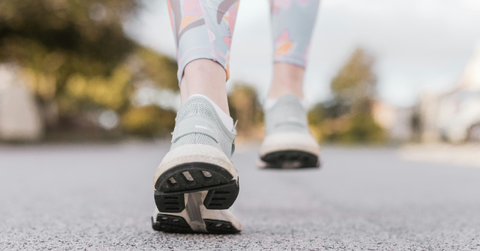 The bottom of a woman's sneaker is visible while she walks