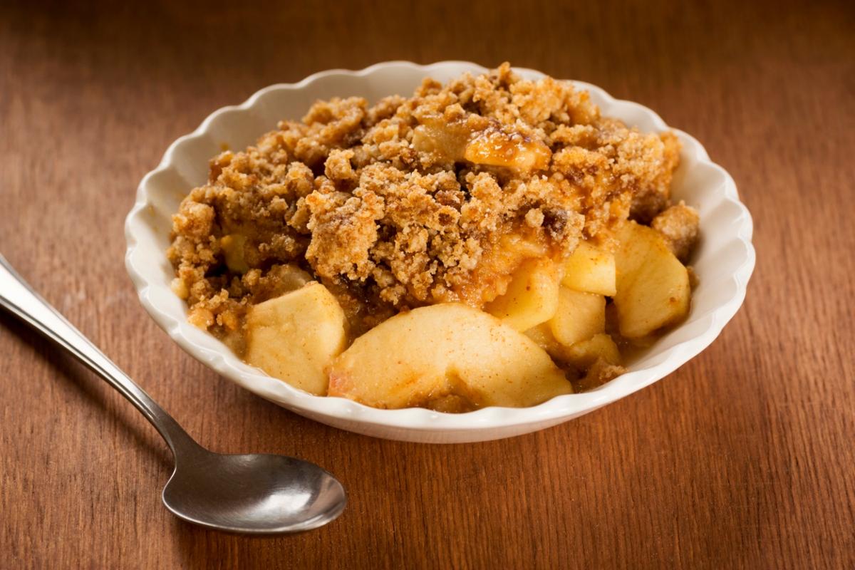 apple crisp in white bowl on wooden table