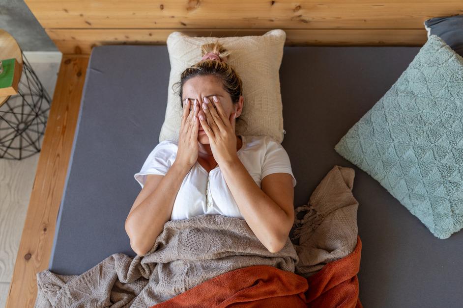 A woman waking up and rubbing her face while in bed.