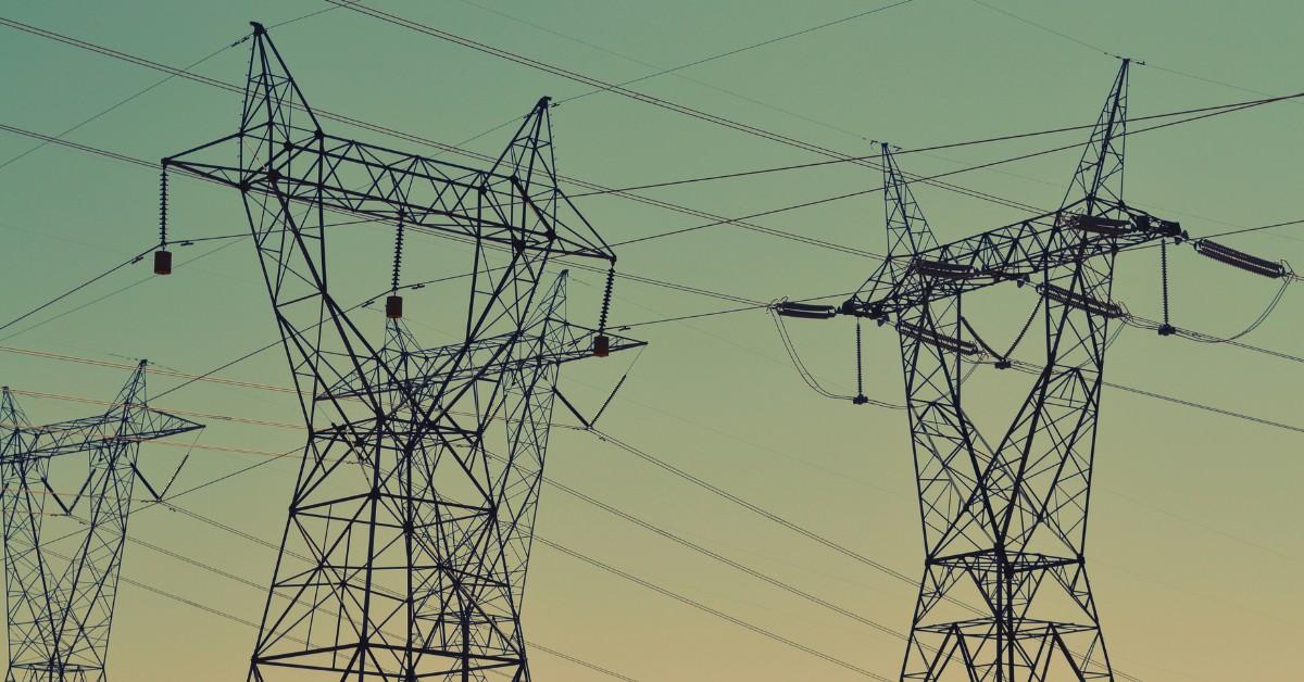 A collection of powerlines stand tall against a greenish sky