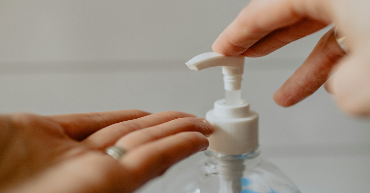 A woman uses a hand sanitizer pump to put sanitizer on her hands