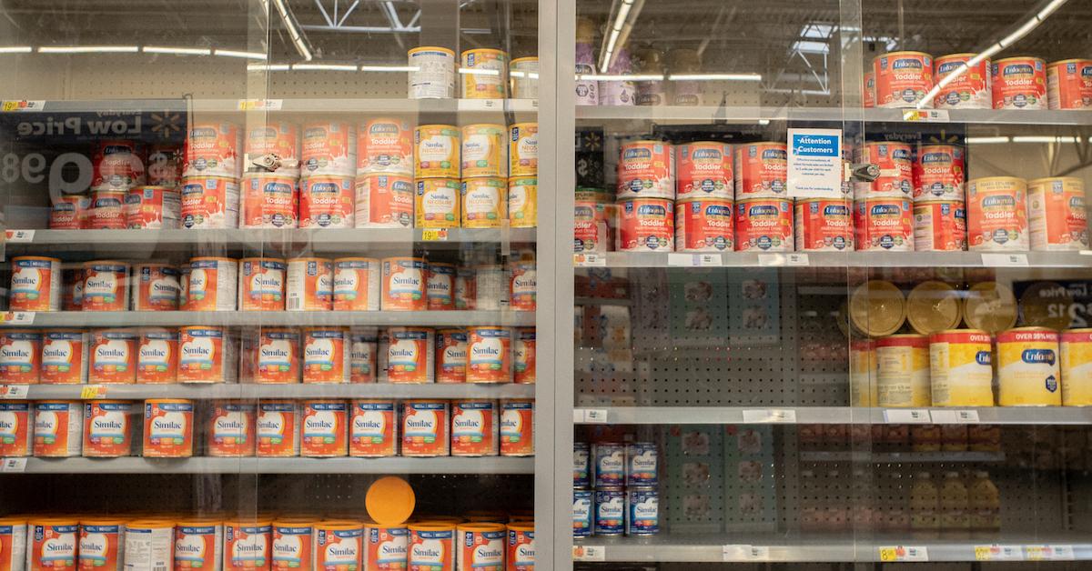 Cans of baby formula behind glass in a store