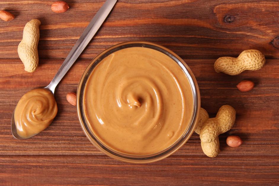 Peanut butter and peanuts on a wooden table. 