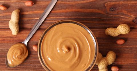 Peanut butter and peanuts on a wooden table.