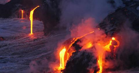 A stream of hot lava from a volcanic eruption flows on an icy mountain and into a river. (Representative Cover Image Source: Unsplash | Marc Szeglat)