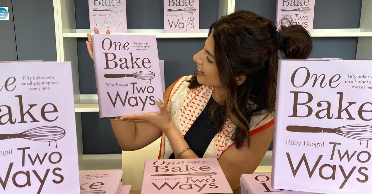 'The Great British Bake Off' star and cookbook author Ruby Bhogal holding her 2024 book 'One Bake, Two Ways: Fifty bakes with an all-plant option every time'