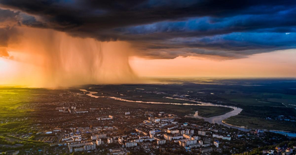 A storm forms in the distance, dropping massive amounts of rain on a city