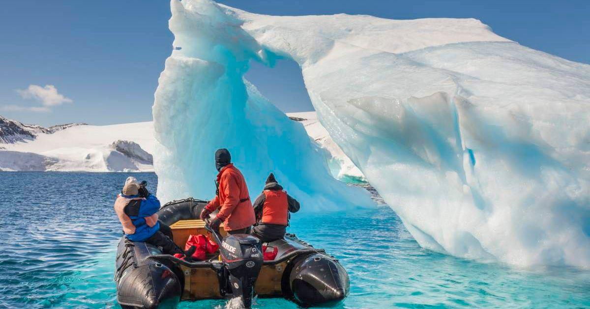 Researchers investigating Antarctic sea ice in front of an iceberg (Representative Cover Image Source: Getty Images | Patrick Endres)