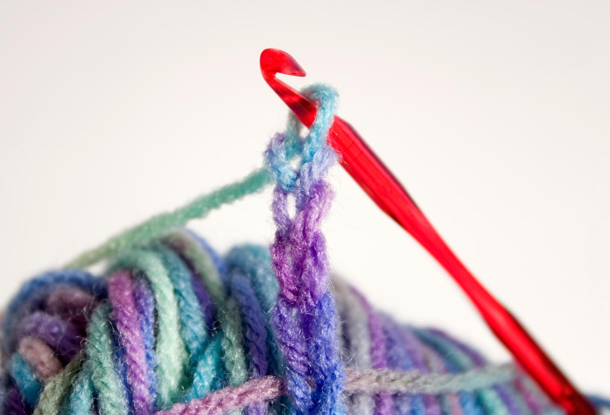 A hook holding a chain of four created with a multi-colored yarn.