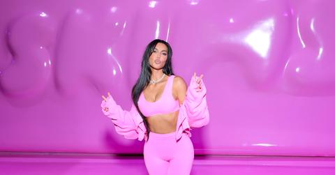 Kim Kardashian poses in a pink outfit in front of a pink SKIMS-branded wall, at the SKIMS Valentine's Shop Pop-Up at Westfield Century City on Feb. 8, 2023 in Los Angeles.
