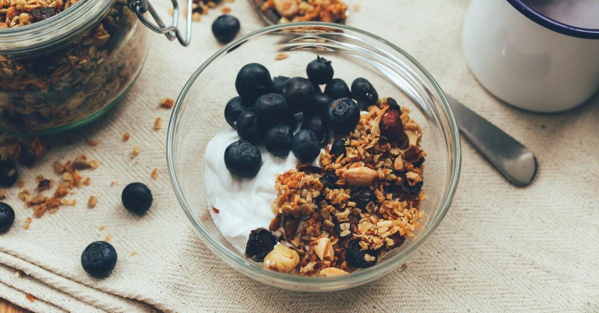 A bowl of yogurt, blueberries, and granola sits on a table