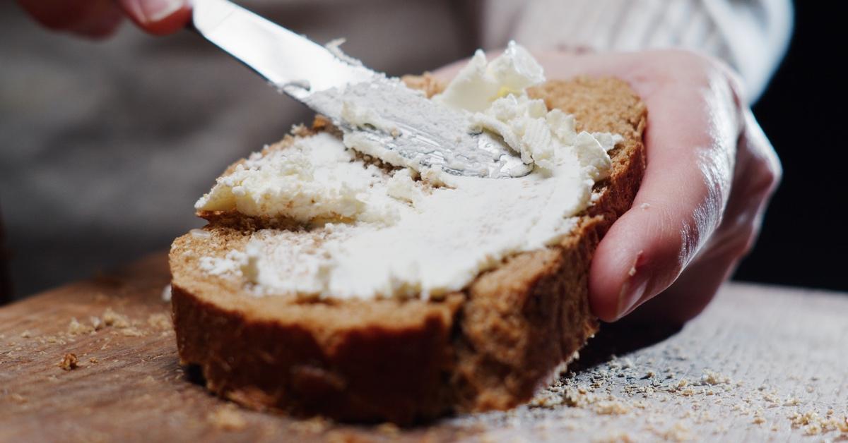 Person spreading cream cheese on bread