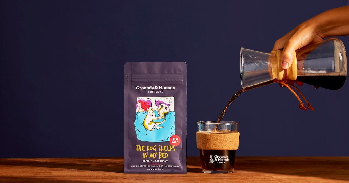 Bag of Grounds & Hounds Coffee Co.'s "This Dog Sleeps in My Bed" brew next to glass of coffee and carafe pouring coffee in.