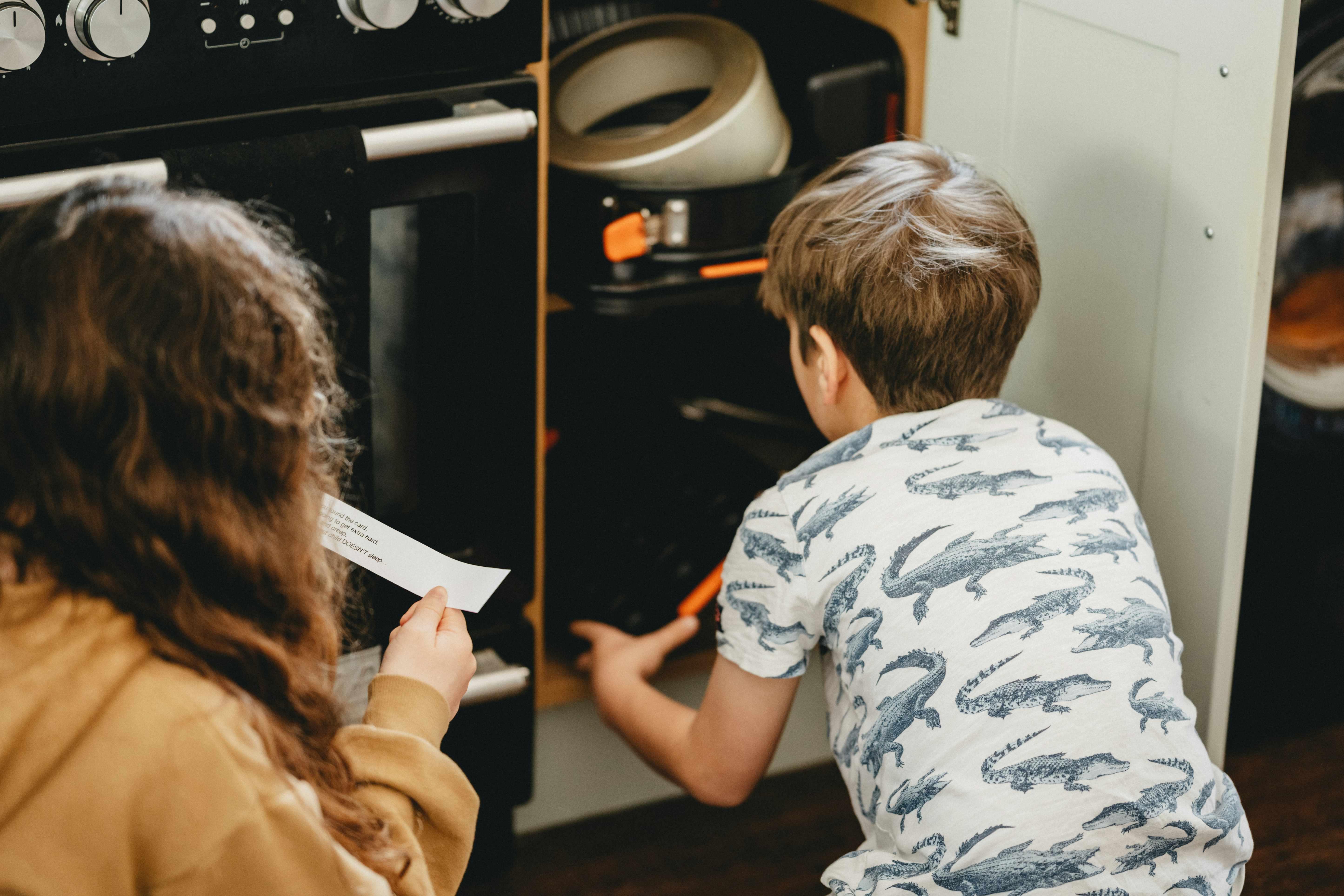 Two kids work together on a scavenger hunt while one teammate reads clues from a piece of paper.