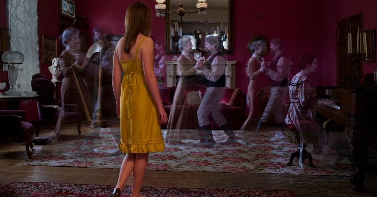 A woman standing in a hotel looking at dancing ghosts