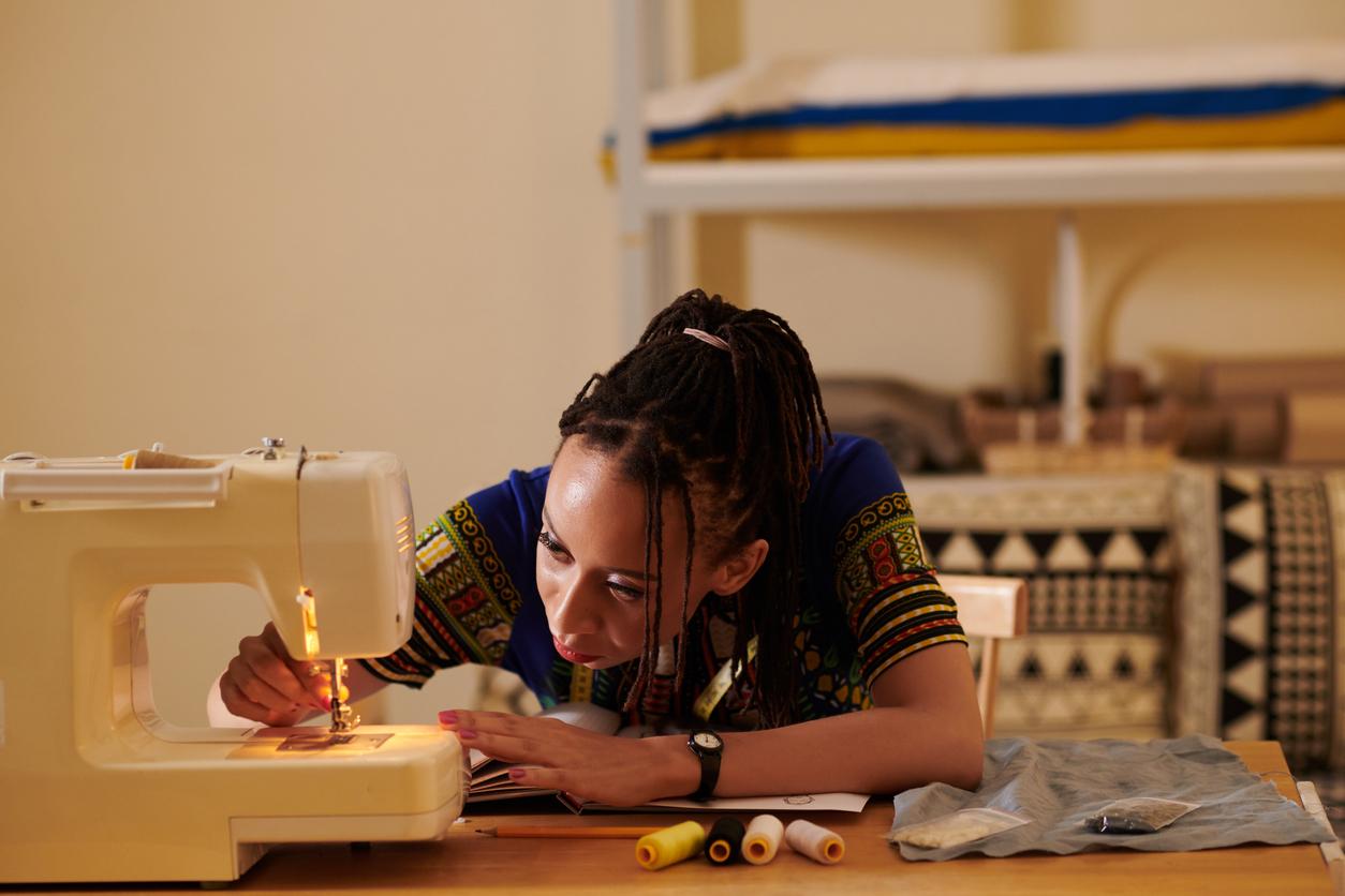 Front-facing view of a person leaning down toward sewing machine while using it.