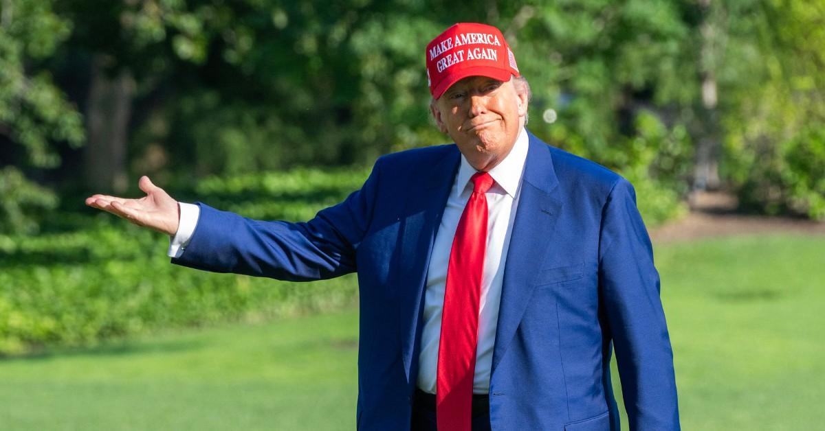 Donald Trump wears a blue suit and a red MAGA hat while arriving at the White House