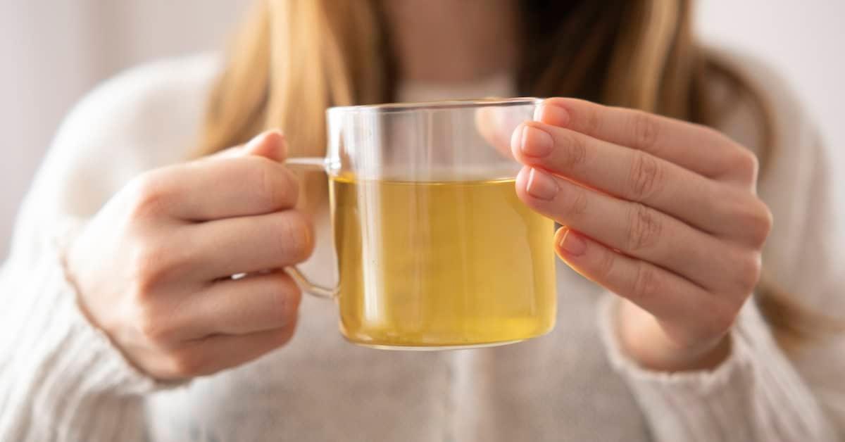 Closeup of person holding a cup of herbal tea.