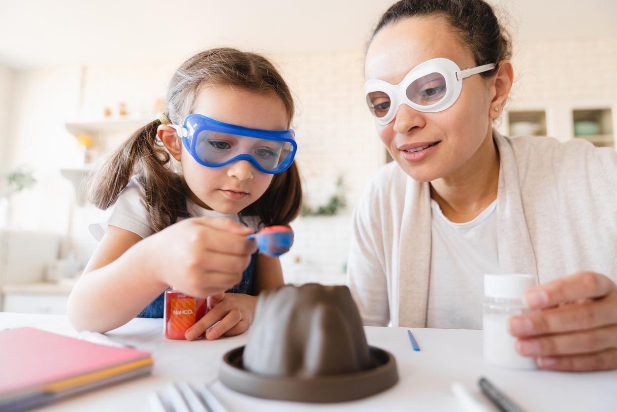 Child and adult working on baking soda volcano science experiment together