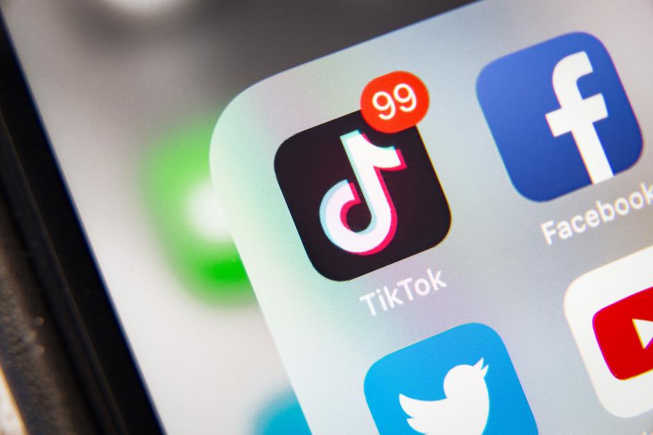 An iPhone screen open to a folder with the Facebook, Youtube, Twitter, and TikTok apps where TikTok has 99 notifications. 